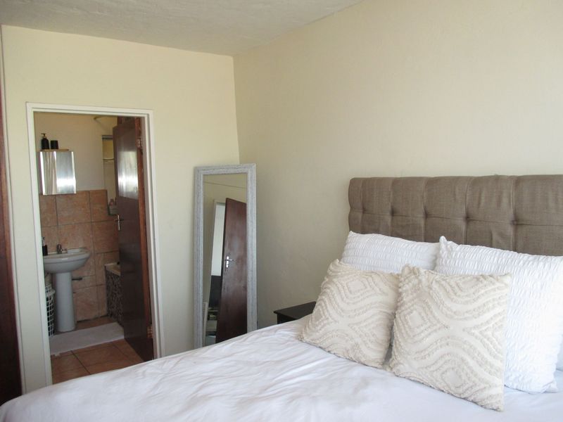 A bedroom featuring neutral walls and an adjoining bathroom with a pedestal basin and tiled finishes.