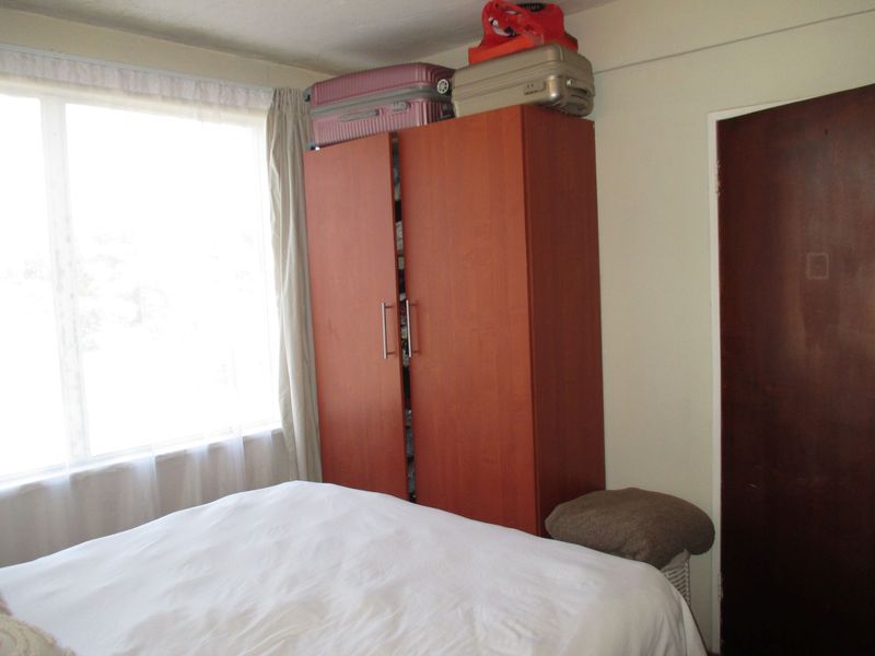 A bedroom featuring a large window and a dark wood internal door, providing a functional space with natural light.