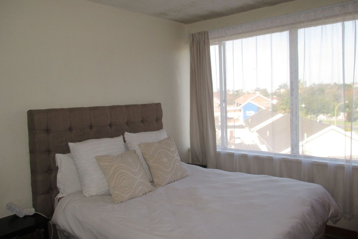 A bedroom featuring a large window with natural light and views, requiring some cosmetic attention to the ceiling and wall finishes.