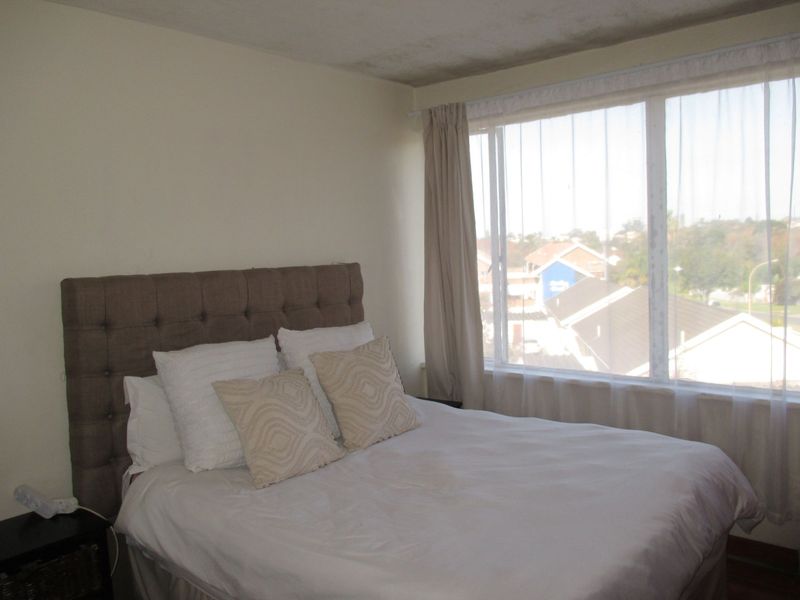 A bedroom featuring a large window with natural light and views, requiring some cosmetic attention to the ceiling and wall finishes.