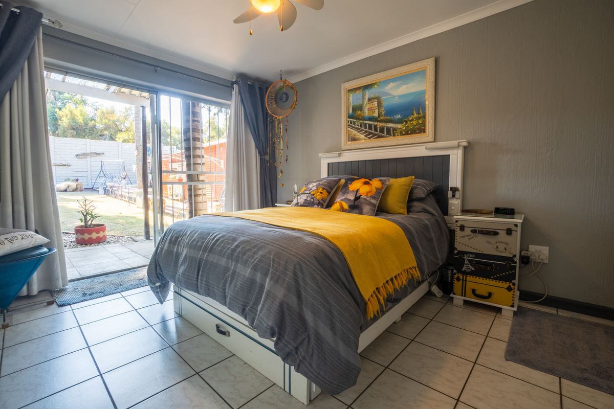 A well-lit bedroom featuring tiled flooring, a ceiling fan, and a sliding glass door providing direct access to the rear garden area.