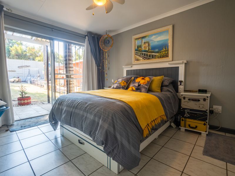A well-lit bedroom featuring tiled flooring, a ceiling fan, and a sliding glass door providing direct access to the rear garden area.