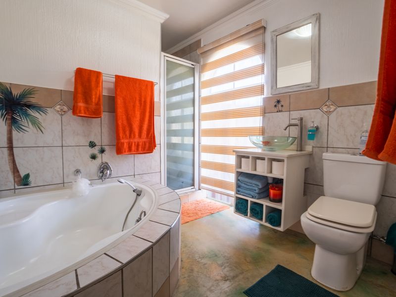 A functional bathroom featuring a built-in corner bathtub, a glass vessel sink vanity, a separate shower enclosure, and decorative tiled walls.