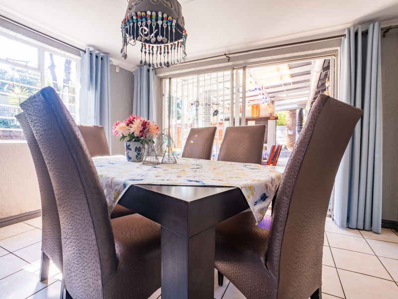 A bright dining room featuring tiled flooring, large windows, and sliding glass doors that provide direct access to the outdoor patio area.