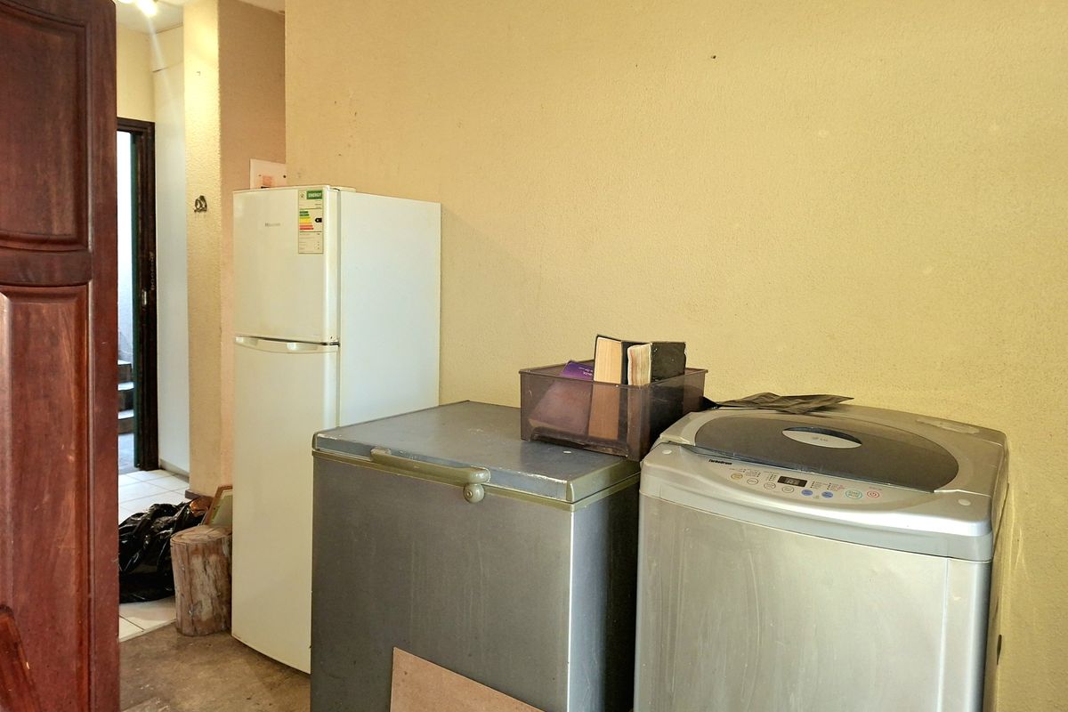 A functional laundry or utility area featuring tiled flooring and space for multiple appliances.