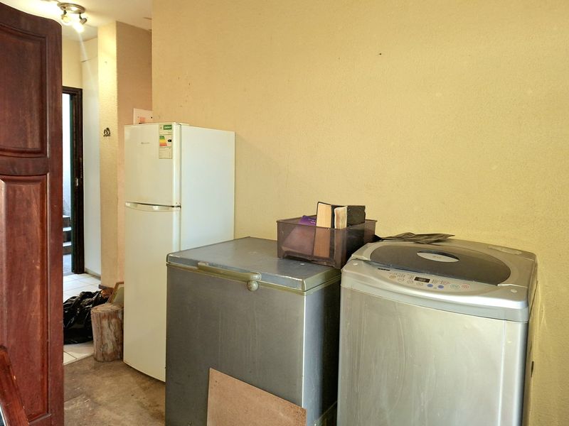 A functional laundry or utility area featuring tiled flooring and space for multiple appliances.
