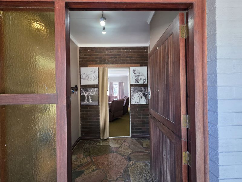 Entrance foyer featuring rustic flagstone flooring and an exposed brick feature wall, leading through a folding door into the main living area.
