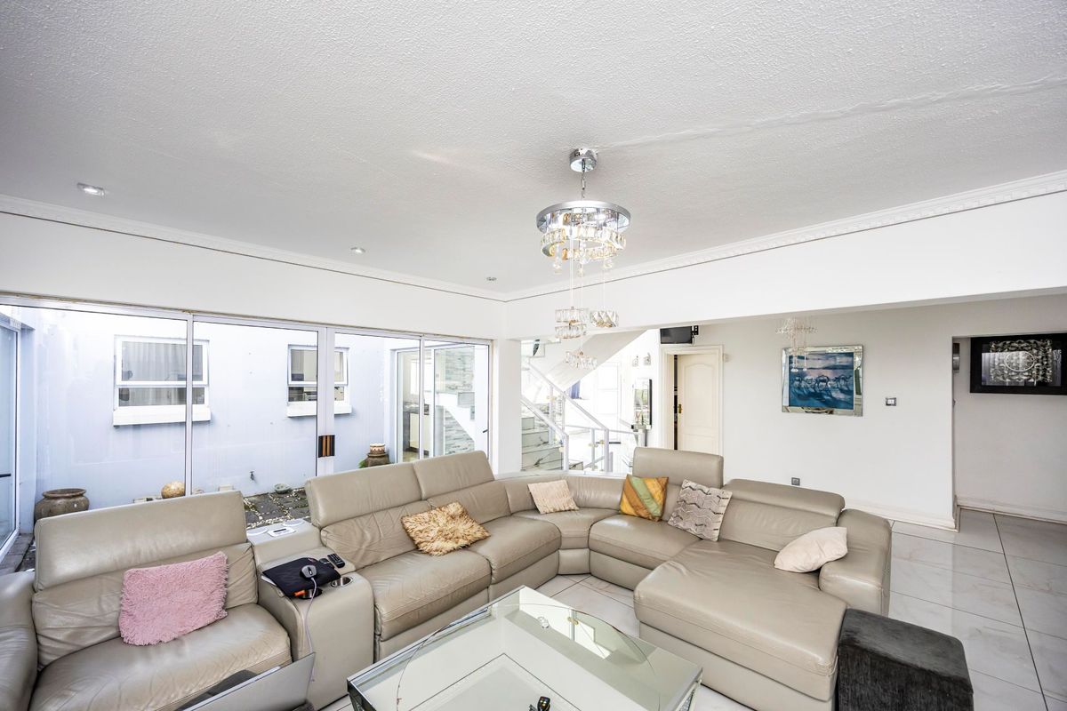 Spacious living room featuring large sliding glass doors, tiled flooring, recessed lighting, and a staircase, offering a bright and open layout.