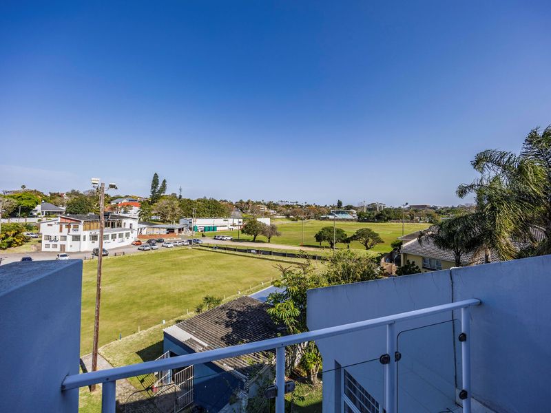 Elevated view from a balcony overlooking a sports field and surrounding neighborhood.