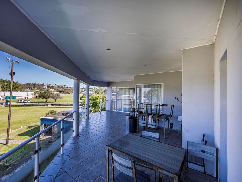 Spacious covered balcony featuring tiled flooring, a modern glass balustrade, and recessed lighting, offering elevated views over the surrounding area.