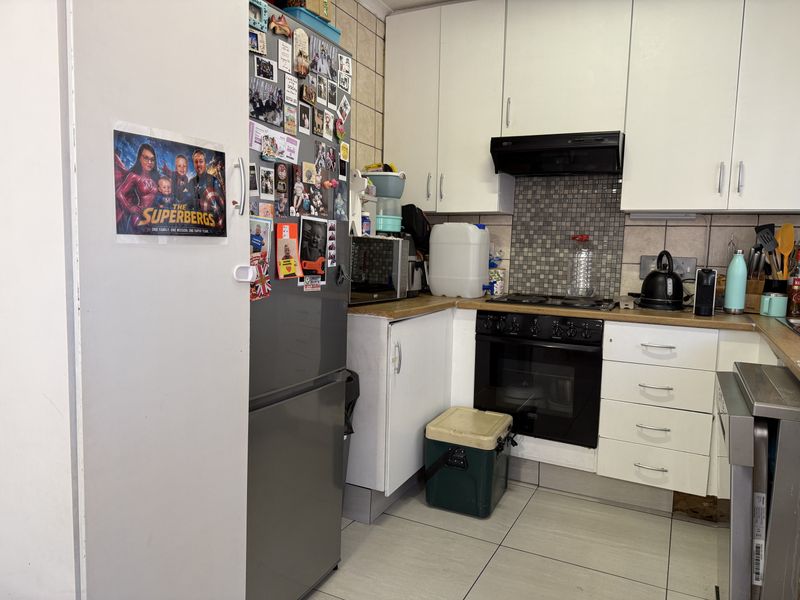 Compact kitchen featuring white cabinetry, built-in oven and hob, tiled splashback, and tiled flooring.