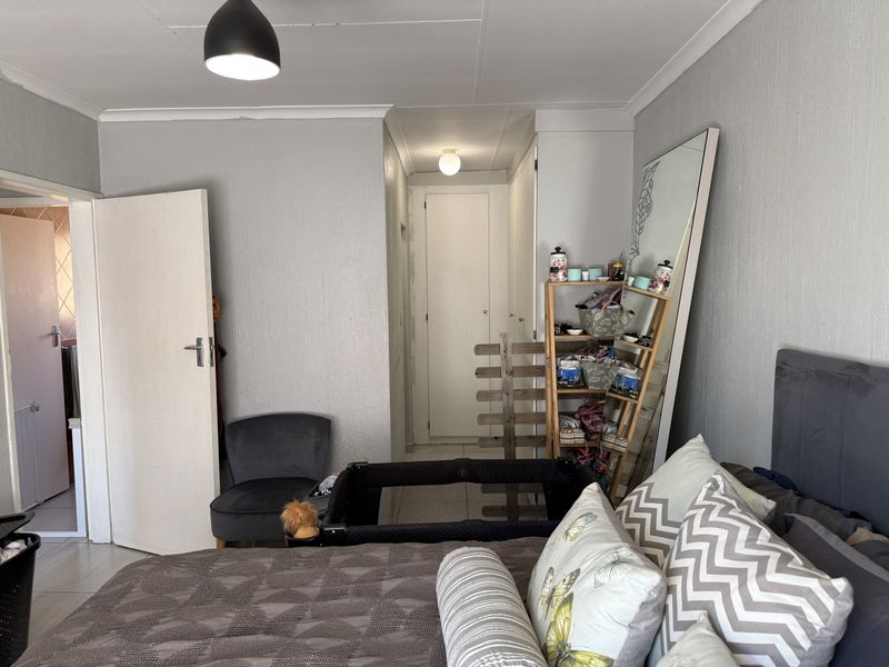 A bedroom featuring tiled flooring and neutral wall finishes, with direct access to an adjoining room or hallway.
