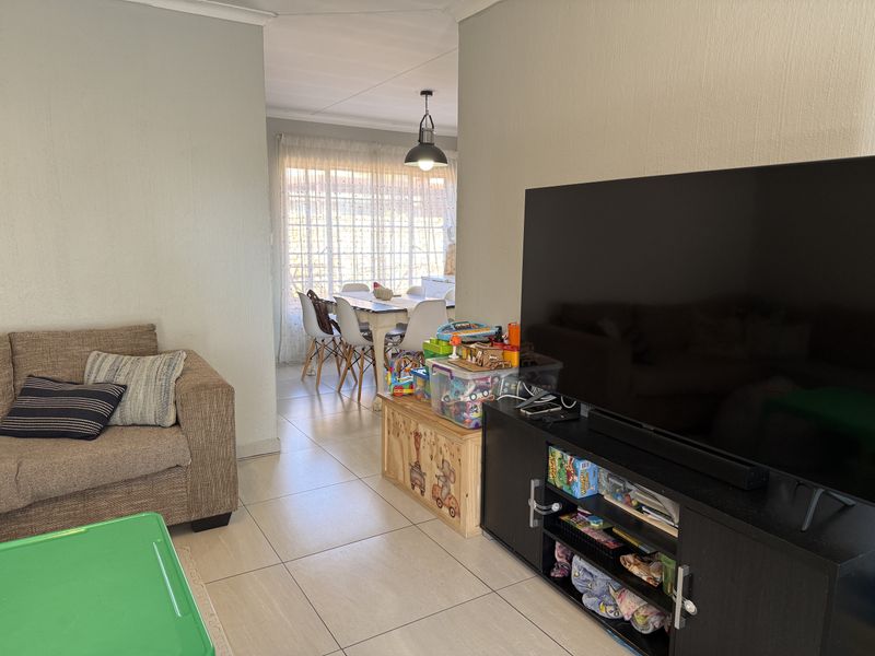 Open plan living and dining area featuring neutral tiled flooring and natural light, providing a functional space for family living.