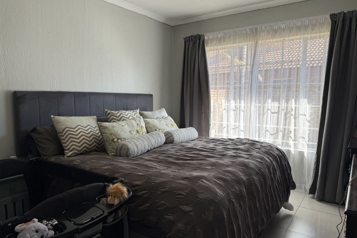 A well-lit bedroom featuring tiled flooring and large windows with curtain tracks, providing a comfortable and functional living space.