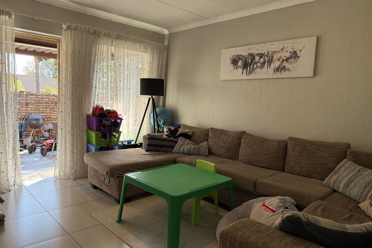 A living room featuring tiled flooring and a sliding glass door providing access to an outdoor patio area.