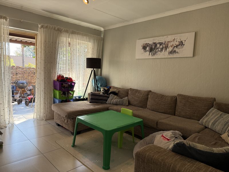 A living room featuring tiled flooring and a sliding glass door providing access to an outdoor patio area.