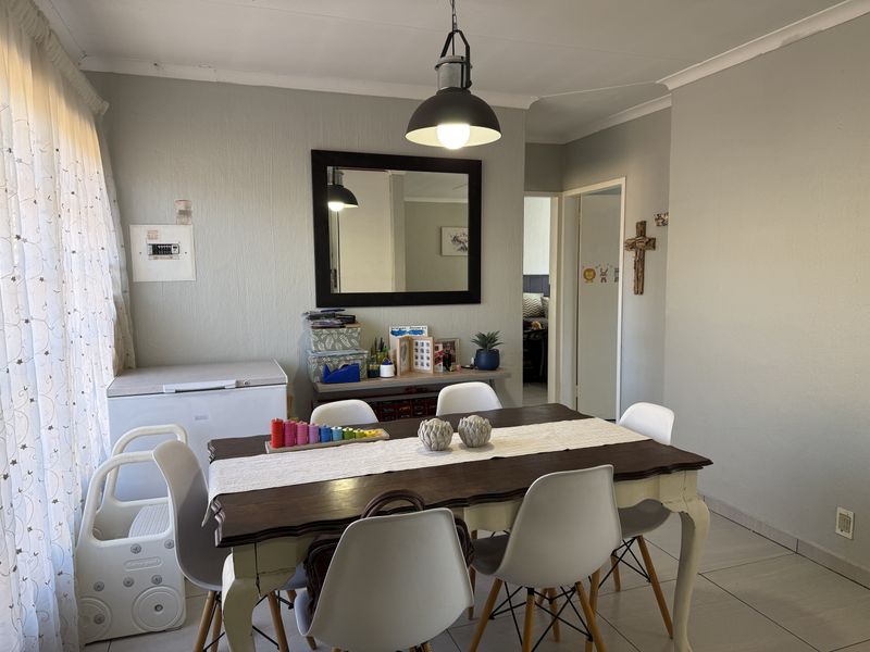 A functional dining area featuring tiled flooring, a central pendant light, and a neutral wall finish, providing a practical space for family meals.