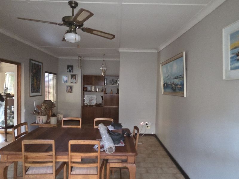 A dining room featuring tiled flooring, a ceiling fan, and built-in wooden cabinetry, with access to an adjacent room through a timber-framed sliding door.