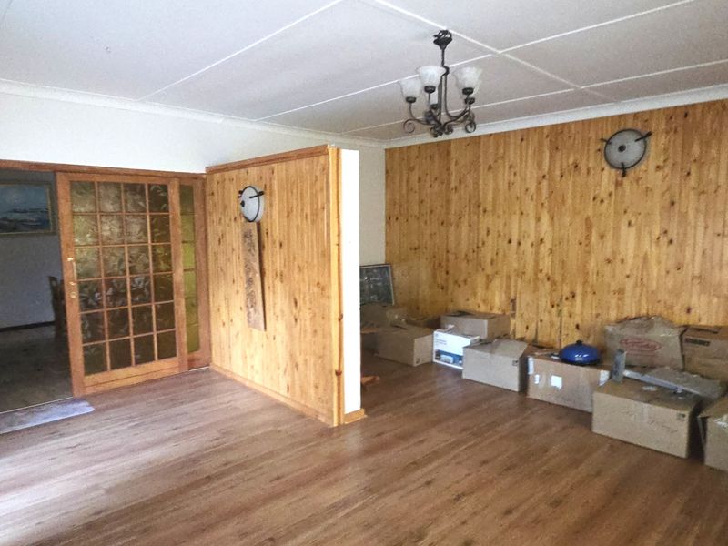 Spacious living area featuring timber wall paneling, laminate flooring, and a sliding glass door leading to an adjacent room.