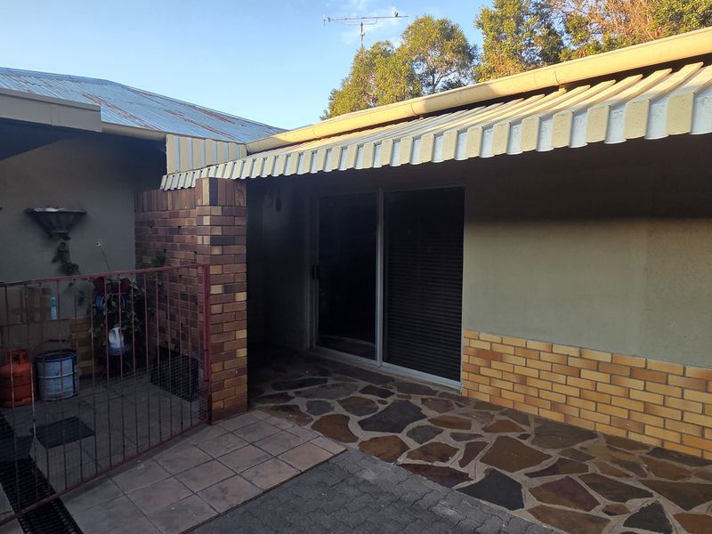 A covered patio area featuring stone paving, brick accents, and a sliding glass door entrance to the home.