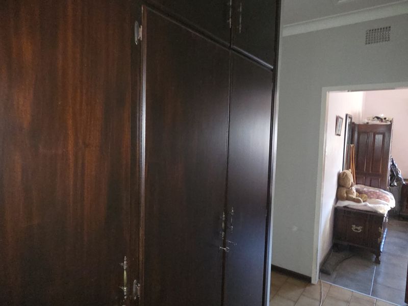 A hallway featuring dark wood built-in cupboards and access to an adjacent bedroom.