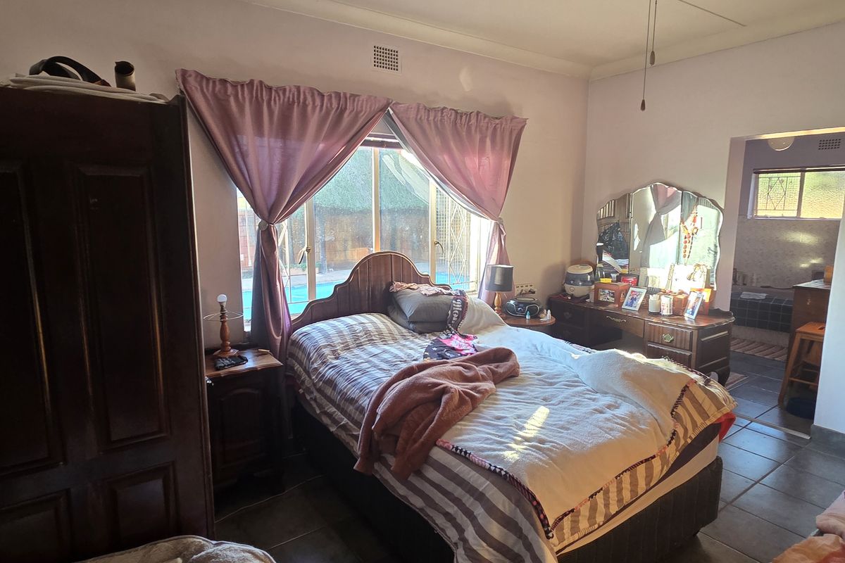 A bedroom featuring tiled flooring, a built-in wardrobe, and direct access to an en-suite bathroom, requiring cosmetic updates to the wall finishes.
