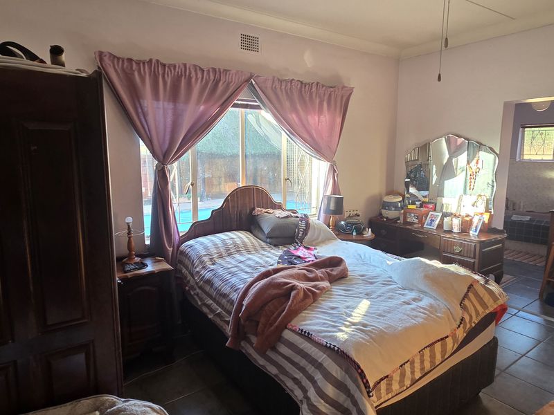 A bedroom featuring tiled flooring, a built-in wardrobe, and direct access to an en-suite bathroom, requiring cosmetic updates to the wall finishes.