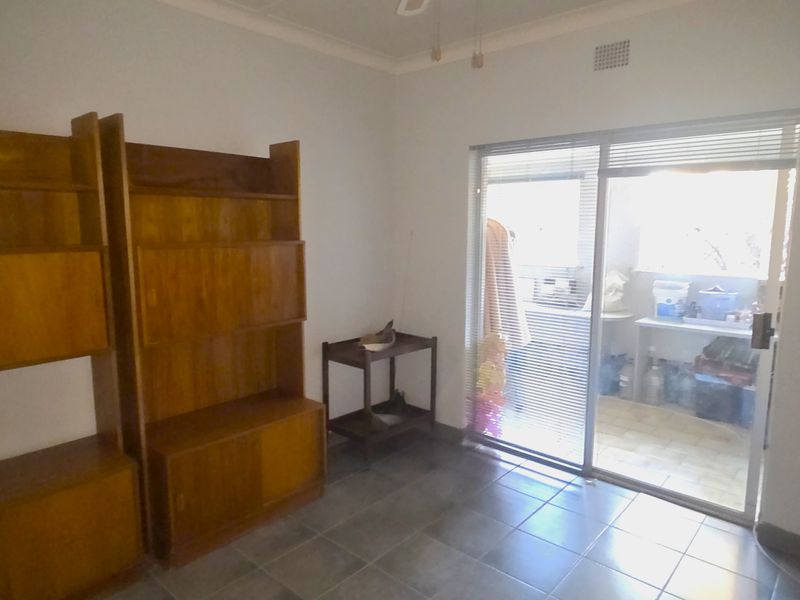 A living area featuring tiled flooring and a sliding glass door providing access to an outdoor space.