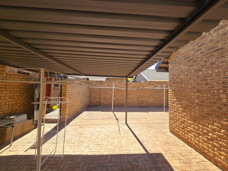 A covered outdoor patio area featuring face brick walls and durable brick paving, providing a functional space for laundry or outdoor utility use.