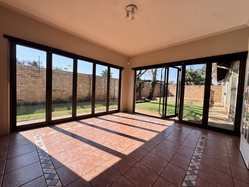 Spacious enclosed patio featuring large folding glass doors that open onto a private garden, providing seamless indoor-outdoor flow.