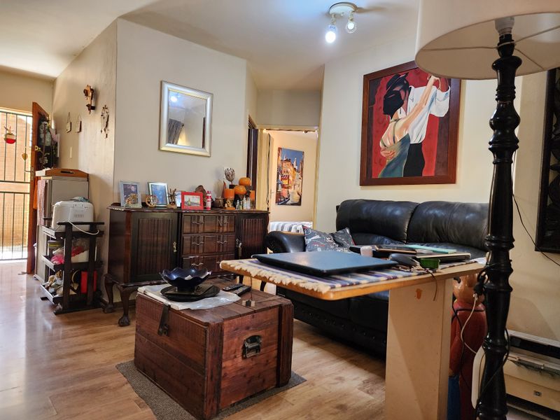 A cozy living room area featuring laminate flooring and direct access to an exterior security gate.