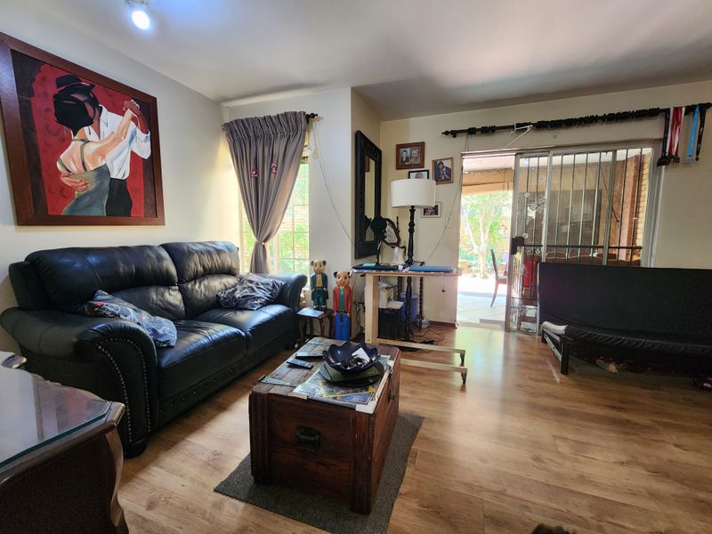 A living room featuring laminate flooring and a sliding glass door with a security gate, providing direct access to the outdoor patio area.