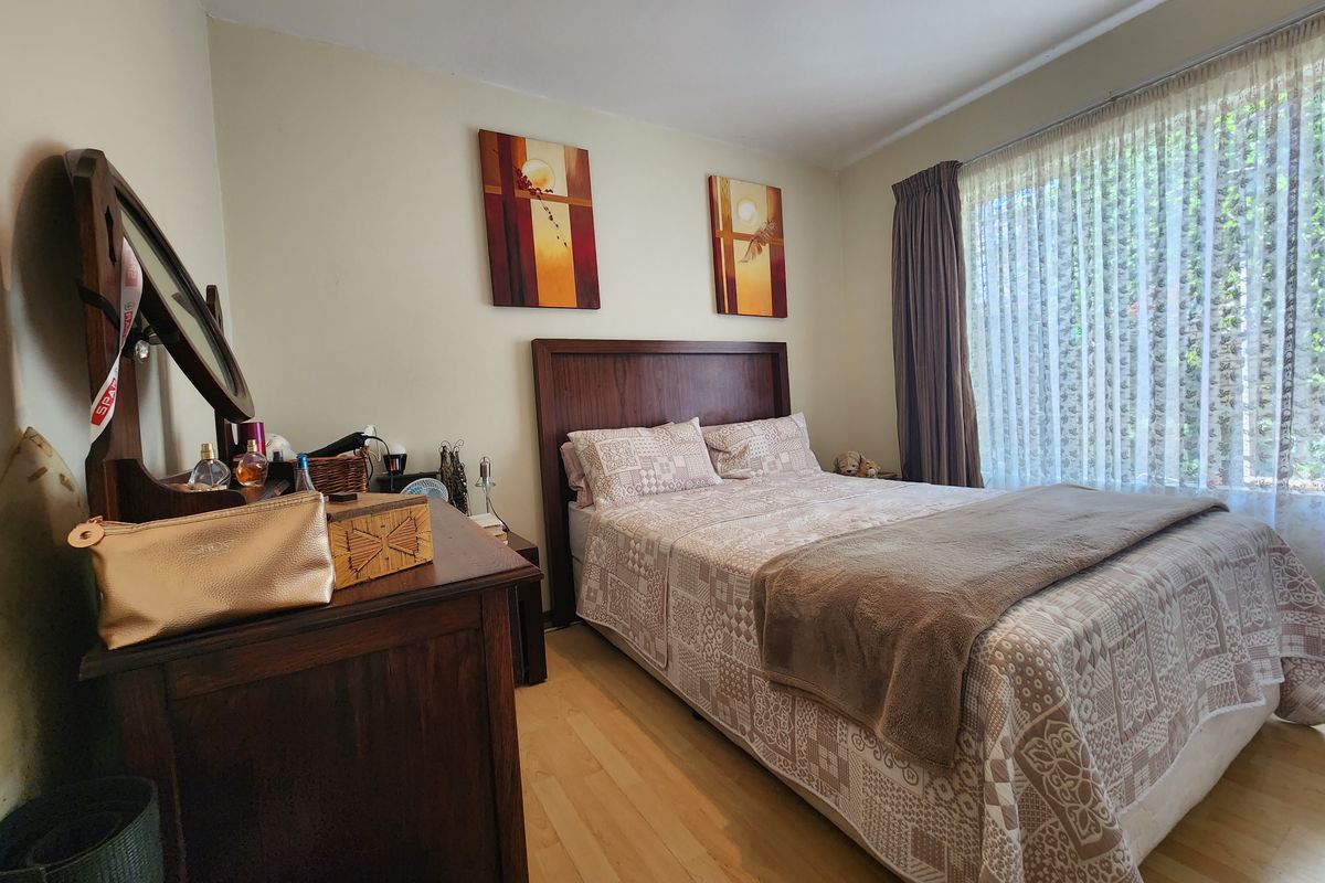 A well-lit bedroom featuring laminate flooring and large windows with curtain tracks, providing a comfortable and functional living space.