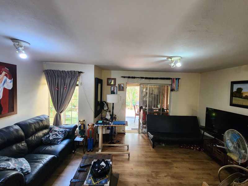 A living room featuring laminate flooring, ceiling lighting, and a sliding door providing access to the outdoor area.