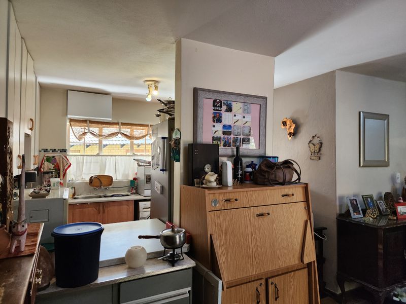 A functional kitchen area featuring built-in cabinetry, a double sink, and a tiled backsplash, connecting to the adjacent living space.