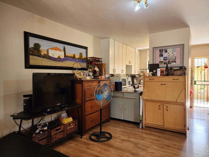 Open plan living area featuring laminate flooring and integrated kitchen cabinetry, providing a functional layout with direct access to the exterior.