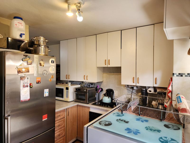 A functional kitchen featuring white upper cabinetry, wood-tone lower cabinets, laminate countertops, and a tiled backsplash.