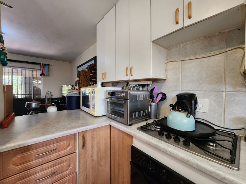 Open plan kitchen area featuring laminate countertops, built-in cabinetry, gas hob, and oven, seamlessly flowing into the adjacent living space.