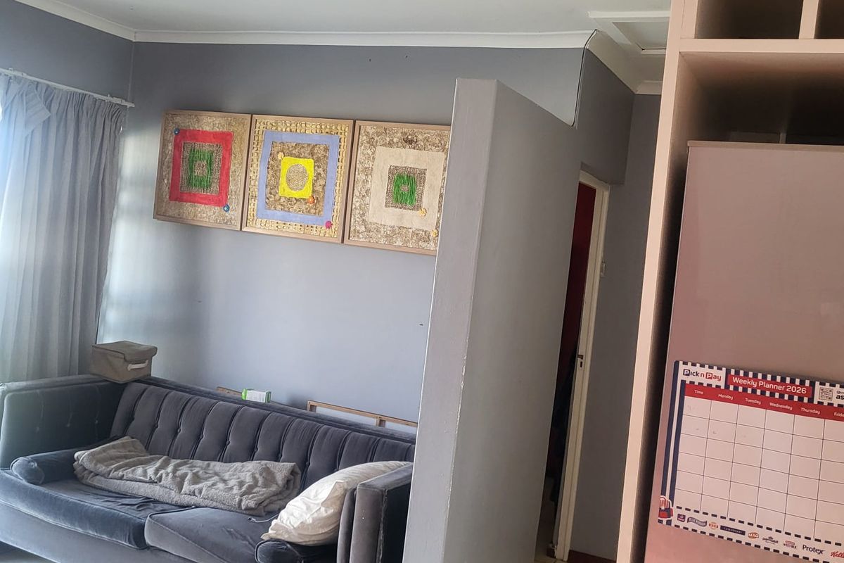 A living area featuring tiled flooring and a partial partition wall, adjacent to built-in cabinetry.