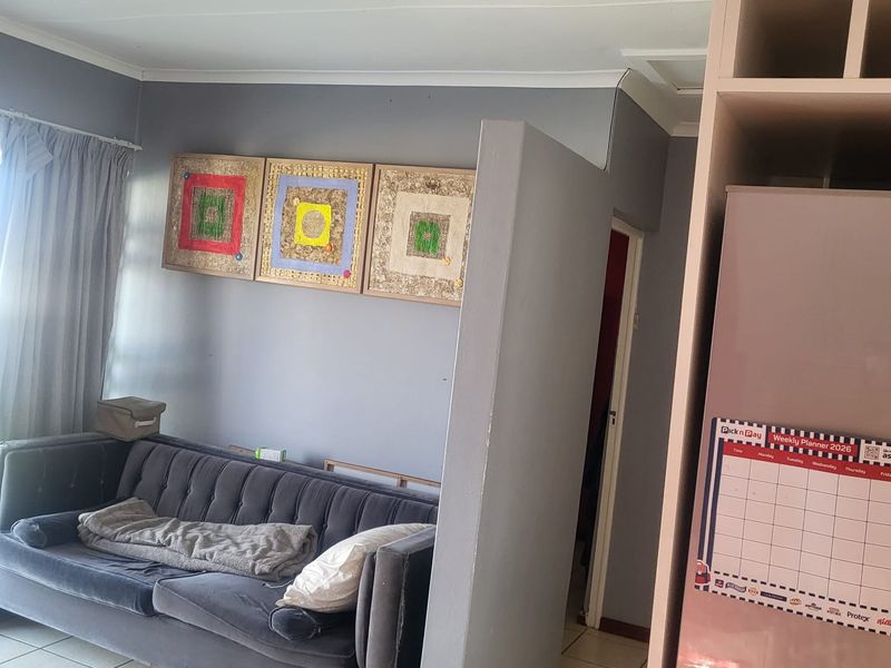 A living area featuring tiled flooring and a partial partition wall, adjacent to built-in cabinetry.