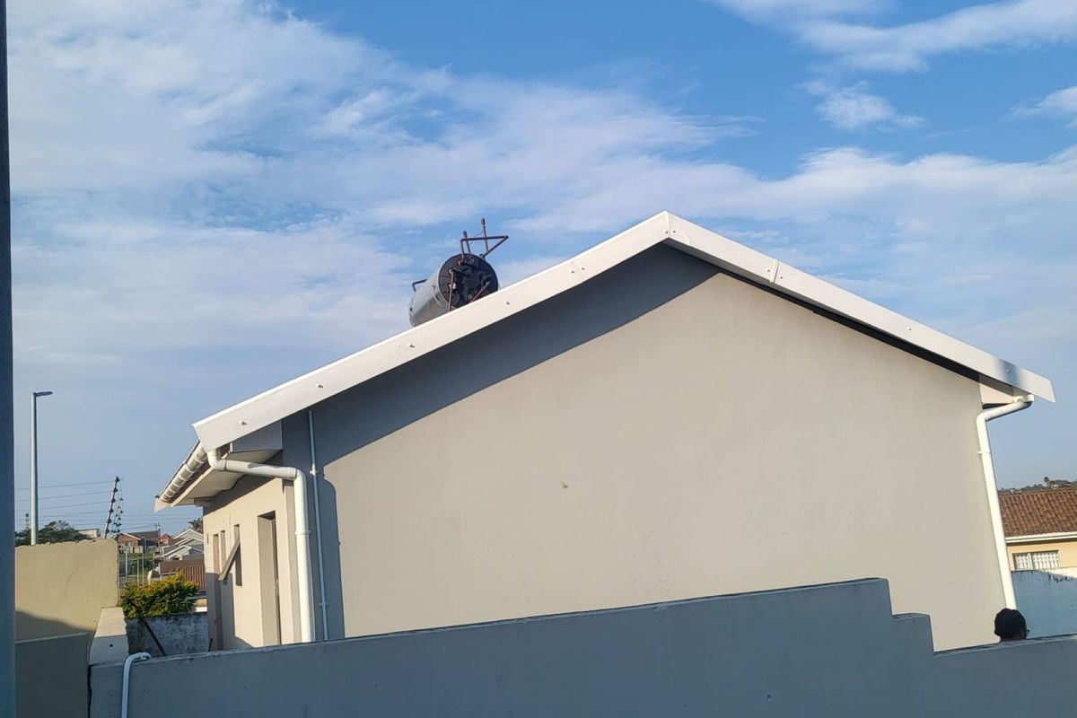 Rear view of the property showing the exterior wall, roofline, and installed solar water heating system.