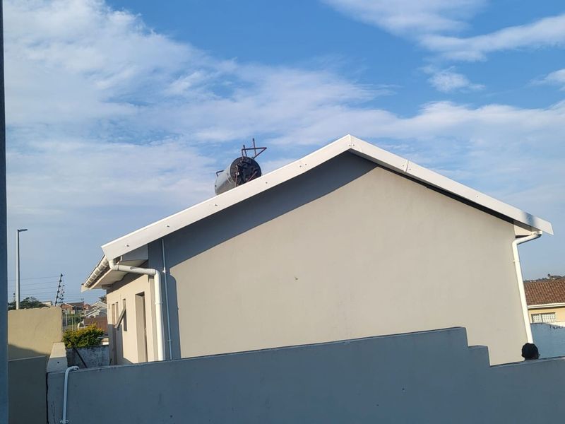 Rear view of the property showing the exterior wall, roofline, and installed solar water heating system.