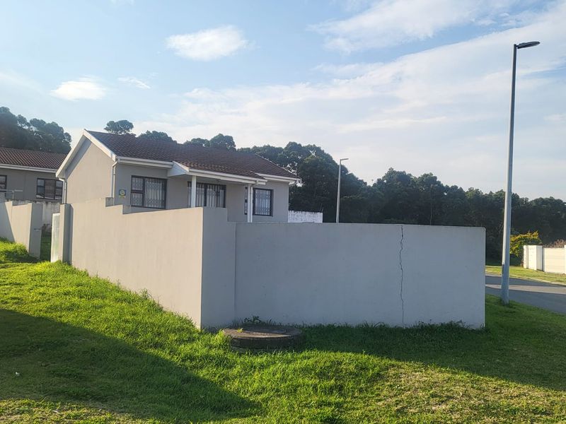 Front view of a residential house featuring a perimeter wall with a visible crack and a tiled roof.