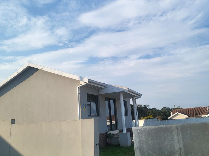 A view of the front exterior of the house featuring a perimeter wall, metal gate, and a covered porch area.