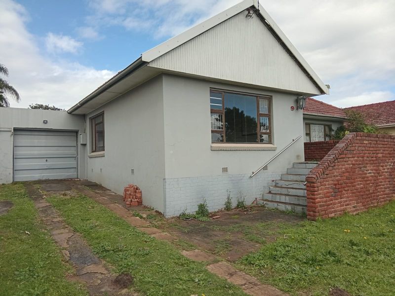 Front elevation of a single-story house featuring a garage, brick staircase with handrail, and paved driveway access.