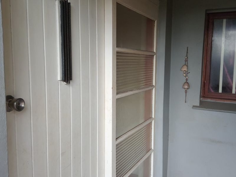Entrance area featuring a timber panelled front door with a sidelight window and security bars on the adjacent window.