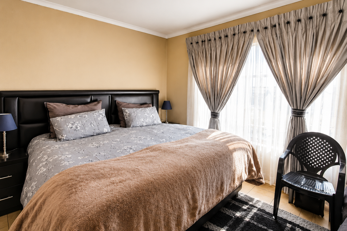 A bedroom featuring tiled flooring and window treatments, providing a functional space with neutral wall tones.