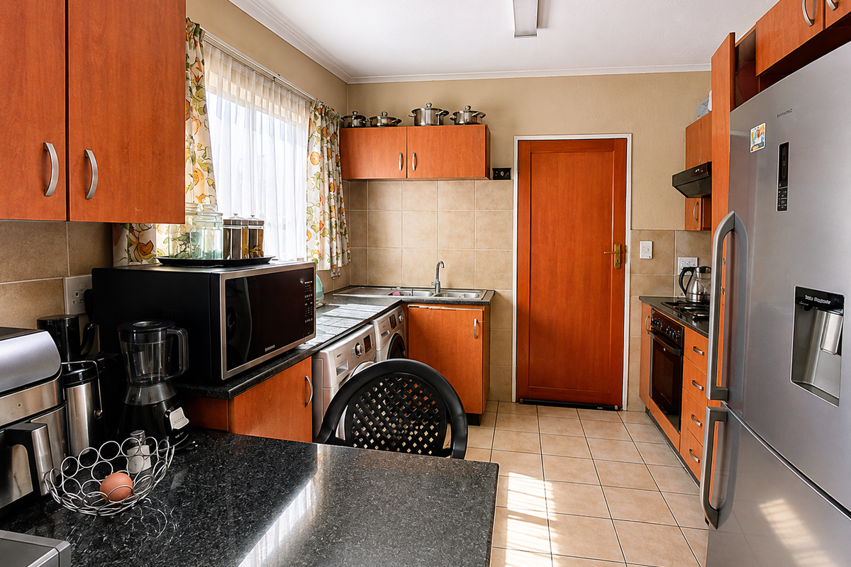 Functional kitchen featuring wood-finish cabinetry, granite countertops, tiled backsplash, and integrated appliances, offering a practical layout with direct access to an exterior door.