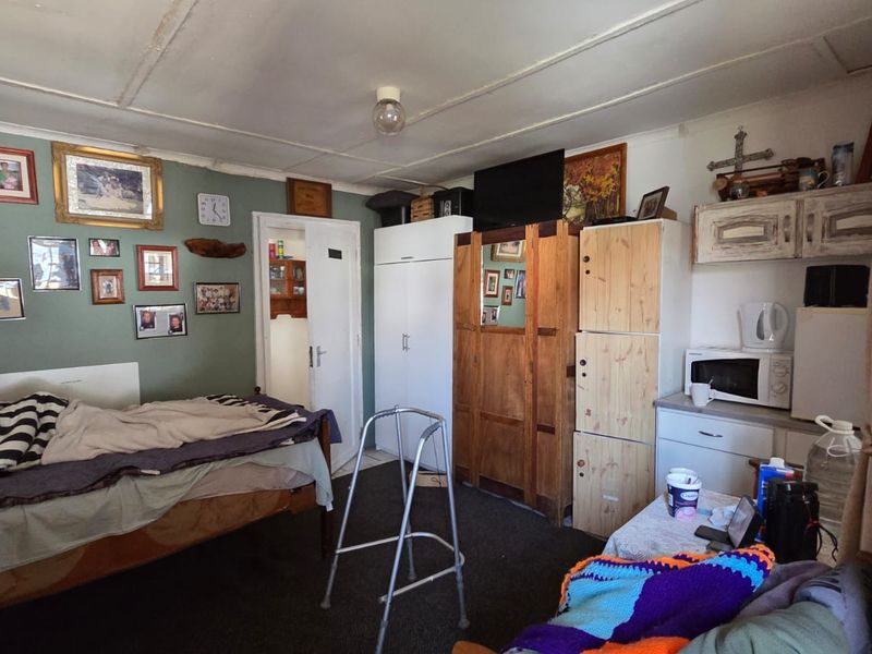 A bedroom featuring built-in cabinetry and ceiling panels, currently showing signs of wear and requiring cosmetic updates to improve the overall condition.