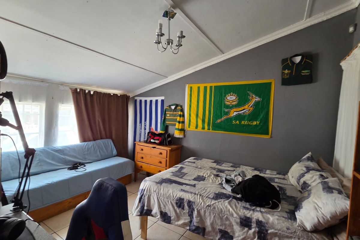 A bedroom featuring tiled flooring and a coved ceiling, currently utilized as a multi-purpose living and sleeping space.